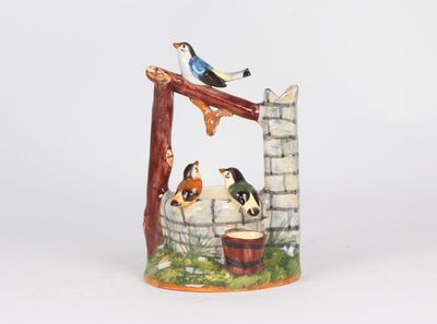 une figurine en céramique représentant un oiseau perché sur un puits