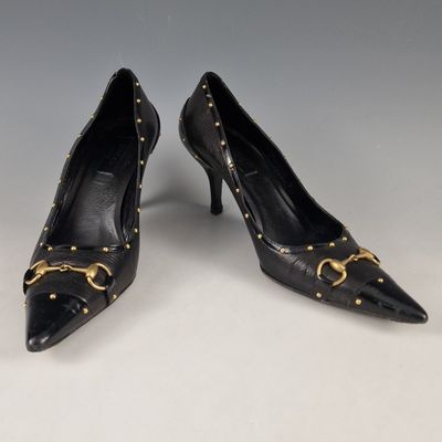 une paire d'escarpins en cuir noir avec des boucles dorées