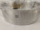 a silver bowl with a spoon in it wrapped in plastic