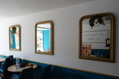three mirrors on the wall above a table and chairs