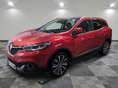 une voiture rouge est garée dans une grande pièce au sol en damier