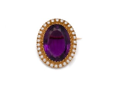 un gros plan sur une bague ornée d'une pierre violette et d'une perle