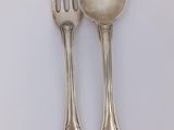 two silver spoons and a fork on a table