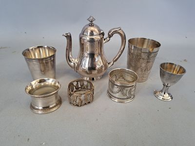 des théières, des tasses et des cuillères en métal argenté posées sur une table