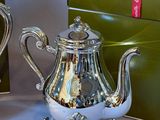 two silver teapots sitting next to each other on a table