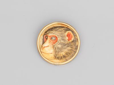 un gros plan du visage d'un singe sur une broche plaquée or