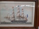 painting of a sailing ship in a wooden frame on a red wall