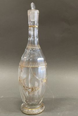 a clear glass bottle with a gold decoration on it
