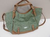 green and tan handbag with leather handles on a white surface
