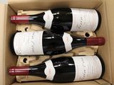 three bottles of red wine in a cardboard box on a table