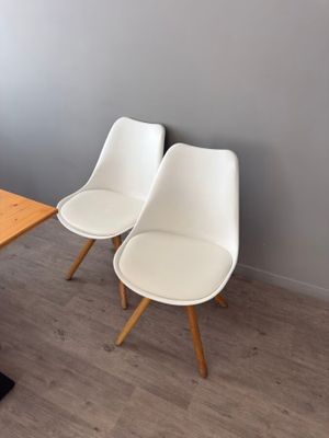 two white chairs sitting next to a table in a room