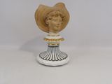 statue d'une femme coiffée d'un chapeau de paille, posée sur un socle blanc