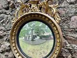 un miroir accroché à un mur de pierre, sur lequel est représenté un oiseau