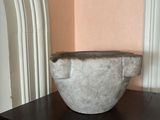 a marble bowl sitting on a table in the corner of a room