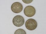 five different coins are arranged in a row on a white surface