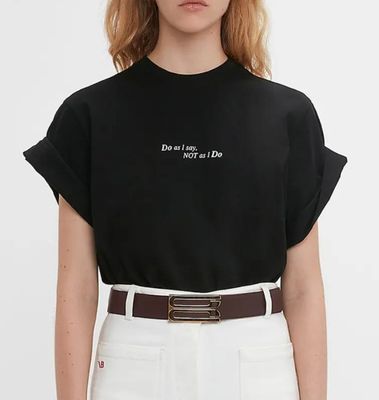 a woman wearing a black shirt and white pants with a brown belt