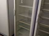 two empty refrigerators in a room with tile flooring
