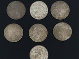 six pièces d'argent sont disposées en cercle sur une surface noire
