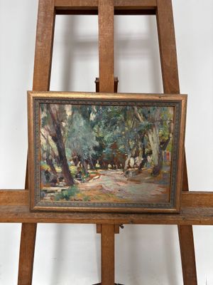 une peinture à l'huile représentant un paysage boisé, posée sur un chevalet en bois