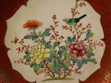 a decorative plate with a bird and flowers on it