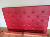 un lit rouge surmonté d'une tête de lit rouge