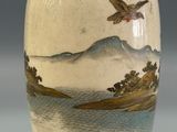 a vase with a bird on it sitting on a table