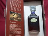 an open box with a bottle of liquor in it sitting on a red cloth