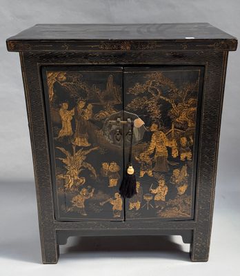 un petit meuble noir orné de motifs dorés
