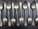 six silver spoons are lined up on a black surface
