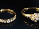 two gold rings with diamonds on a black surface