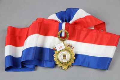 un ruban rouge, blanc et bleu sur lequel est accrochée une médaille d'or