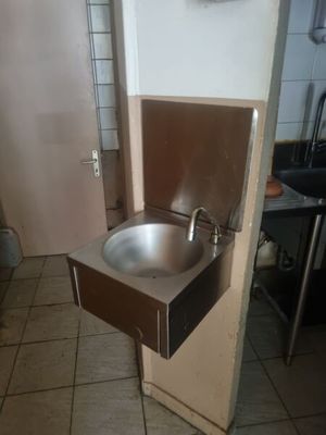 a sink in the corner of a kitchen with a door open
