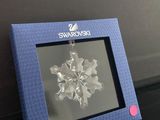 une décoration en forme de flocon de neige dans un cadre bleu, posée sur une table noire