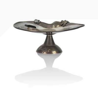 a silver plate with a bird on it on a stand