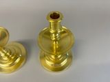 two gold candlesticks sitting on a white surface