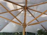 a white umbrella with a wooden pole on a patio