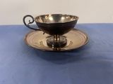 une tasse et une soucoupe plaquées argent posées sur une nappe bleue