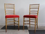 une paire de chaises « Chiavata » dorées avec des coussins rembourrés rouges