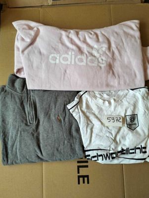 trois t-shirts posés sur une boîte en carton