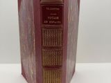 un vieux livre à la couverture rouge posé sur une table blanche