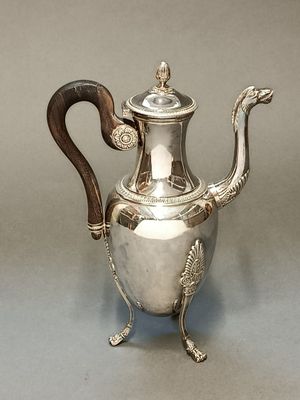 une théière ancienne en argent, munie d'une poignée en bois et posée sur un socle