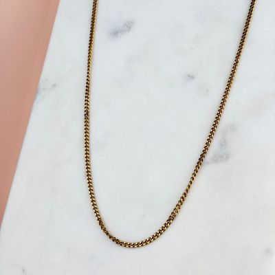 a gold chain necklace on a marble surface