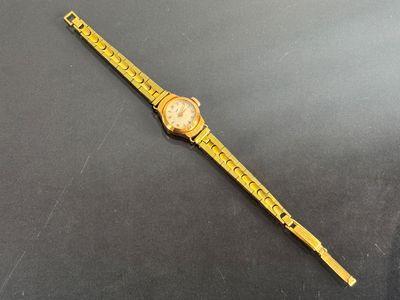 a close up of a watch on a black surface with a ruler