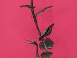 a tall metal plant with a flower on top of it