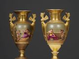 deux vases en or décorés de peintures, posés sur une table