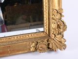 a mirror with a gold frame on a white wall