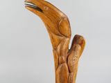 une image représentant une sculpture en bois d'un oiseau, la tête levée vers le ciel