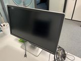 a computer monitor sitting on a desk with a fan