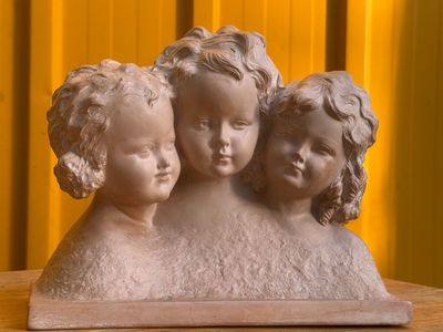 une statue représentant trois enfants assis sur une table en bois