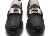 pair of black and white shoes with silver buckles on a white surface